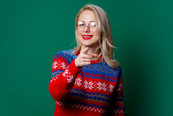 Beautiful woman in Christmas sweater and glasses on green background