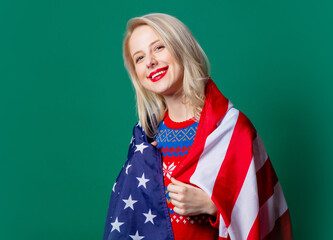 Beautiful woman in Christmas sweater and USA flag on green background