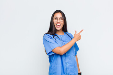 pretty woman looking excited and surprised pointing to the side and upwards to copy space
