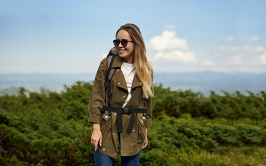 Attractive girl in sunglasses smiling . Traveller is looking to the right side of herself . Concept of tourist at the head of big mountain