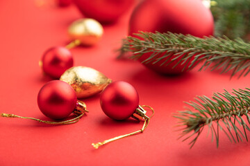 Christmas or New Year composition. Decorations, red balls, fir and spruce branches, on a red background. Side view, selective focus.