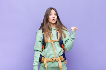 pretty woman looking astonished in disbelief, pointing at object on the side and saying wow,...