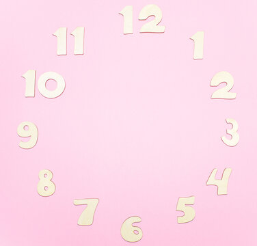 Сlock made of wooden letters arranged in a circle on a pink background. Concept of time. Copy space, mock up.