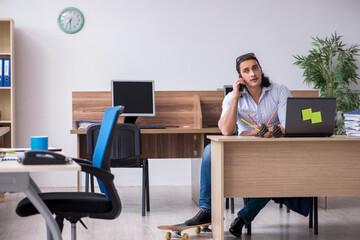 Young male employee with skateboard in the office