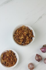 Bawang Merah Goreng or fried shallots, popular Indonesian food topping. Served on white ceramic bowl. Isolated background, copy space.