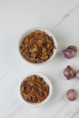 Bawang Merah Goreng or fried shallots, popular Indonesian food topping. Served on white ceramic bowl. Isolated background, copy space.