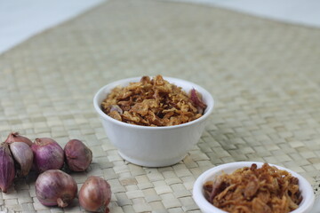 Bawang Merah Goreng or fried shallots, popular Indonesian food topping. Served on white ceramic bowl. Isolated background, copy space.