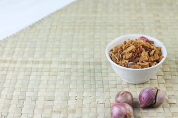 Bawang Merah Goreng or fried shallots, popular Indonesian food topping. Served on white ceramic bowl. Isolated background, copy space.
