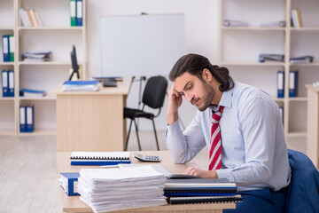 Fototapeta premium Young male employee unhappy with excessive work