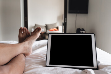 Digital tablet, blank black screen on bed with legs