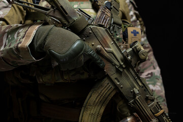 Close-up of a modern machine gun in the hands of a military man dressed in camouflage and full...