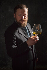Solid confident bearded man in suit with glass of whisky