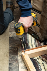 Fototapeta premium The carpenter uses a drill to tighten the screws to the plank