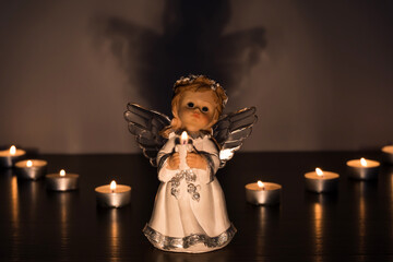 White Christmas angel with lighted candles in the Church. Spiritual deity in religion.