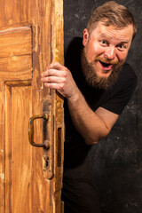Cheerful bearded man peering out of the door