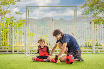 Little cute kid boy in red football uniform and his trainer or father playing soccer, football on...