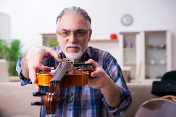 Senior male repairman repairing musical instruments at home