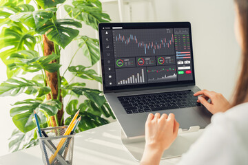 Stock exchange market concept, businesswoman trader looking computer with graphs analysis candle line on table in office, diagrams on screen.