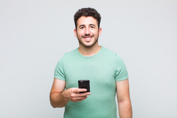 young man smiling happily with a hand on hip and confident, positive, proud and friendly attitude