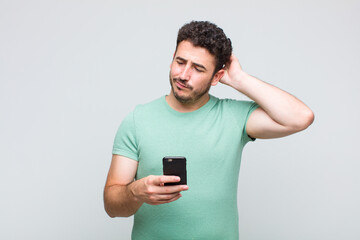 young man feeling puzzled and confused, scratching head and looking to the side