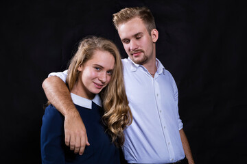Young beautiful couple studio portrait on black background.