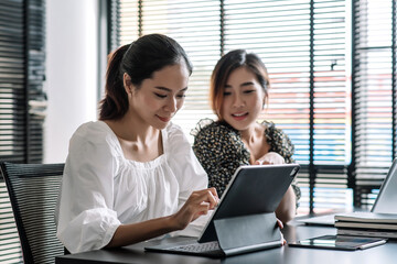 Two young asian businesswoman working together help cooperate on project in teamwork at office.