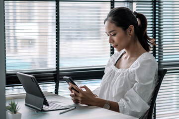 Young asian happy cheerful businesswoman using smartphone in office.