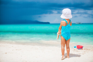 Fototapeta na wymiar Adorable little girl playing with beach toys on white tropial beach