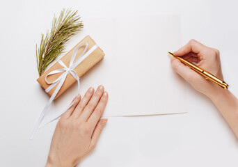 Girl writing blank note with spruce branch and gold pen on white background