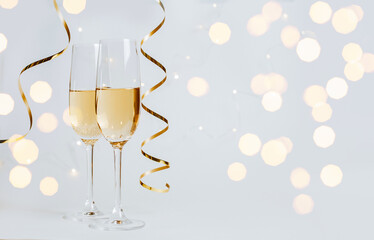 Two glasses of champagne with lights and ribbons on a white background holiday