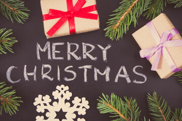 Inscription Merry Christmas, wrapped gifts with ribbon and spruce branches. Decoration for christmas time