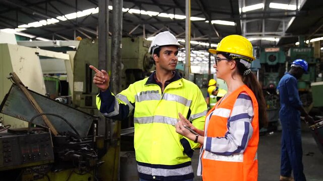 Engineers and skilled technicians are maintaining machinery. Professional technicians are holding a tablet to control work in industrial plants.
