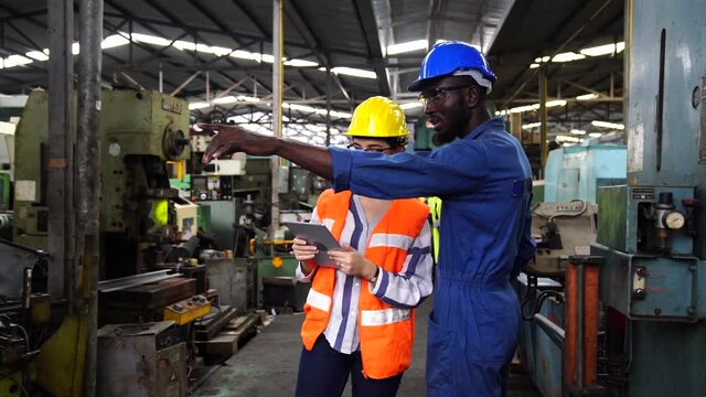 Professional technicians and engineers group wearing protective clothing are working in the industrial plants. Hold the tablet in your hand to see how the machine works.