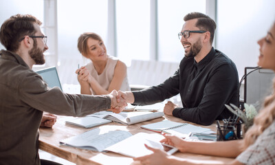 smiling business partners shaking hands at a business meeting.