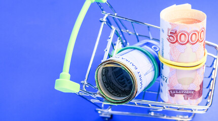Russian rubles in a grocery basket on a blue background. Financial crisis, ruble devaluation concept. Selective focus.