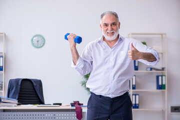 Aged male employee doing physical exercises during break