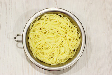Pasta, spaghetti in a metal dushlog on an old and vintage wooden table. served ready for dinner. Close. with copy space. horizontal