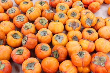 Ripe orange persimmons. on the table in the market. A bunch of organic persimmon fruits at a local farmers market. Persimmon background. Flat lay. Copy space for text and content.
