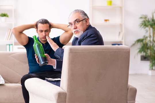 Alcohol addicted young man visiting old male psychologist - Powered by Adobe