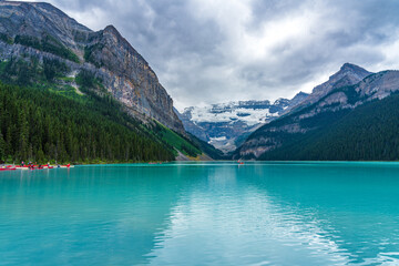 Canoeing on Lake Louise in summer day. Tourists enjoy leisure water activities on the turquoise...