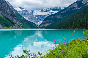 Lake Louise in sunmmer sunny day morning. Blue sky and white clouds reflected on the turquoise color lake water surface. Beautiful landscape in Banff National Park, Alberta, Canada.