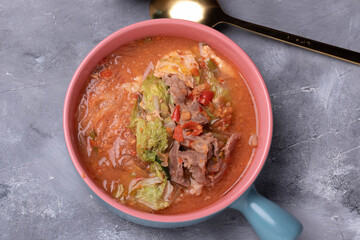 Suki, pork and vegetables in ceramic cup, gray background
