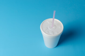 Vaso de plástico blanco aislado sobre fondo azul.