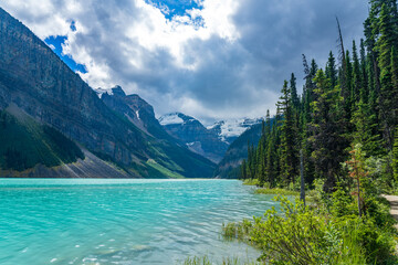 Fototapeta na wymiar Lake Louise in summer sunny day morning. Blue sky and white clouds reflected on the turquoise color lake water surface. Beautiful landscape in Banff National Park, Alberta, Canada.