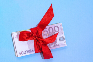 Euro banknotes five hundred on a stack with red bow on a blue background. Gift, bonus or reward concept.