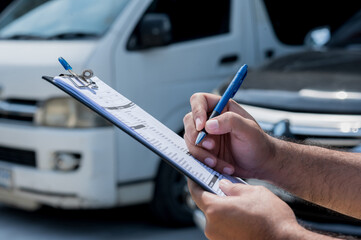 A car maintenance worker is checking a list of items for car maintenance for a workshop customer.