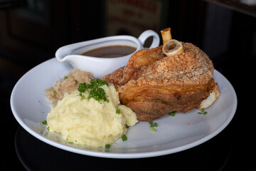 Crispy German or Bavarian pork knuckle with Sauerkraut, potato mash and gravy