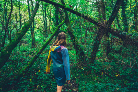 Young woman in raincoat walking in the forest