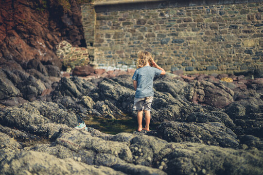 Preschooler standing by rock pool on the beach