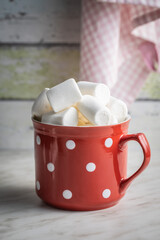 White sweet marshmallows candy in mug on kitchen table.